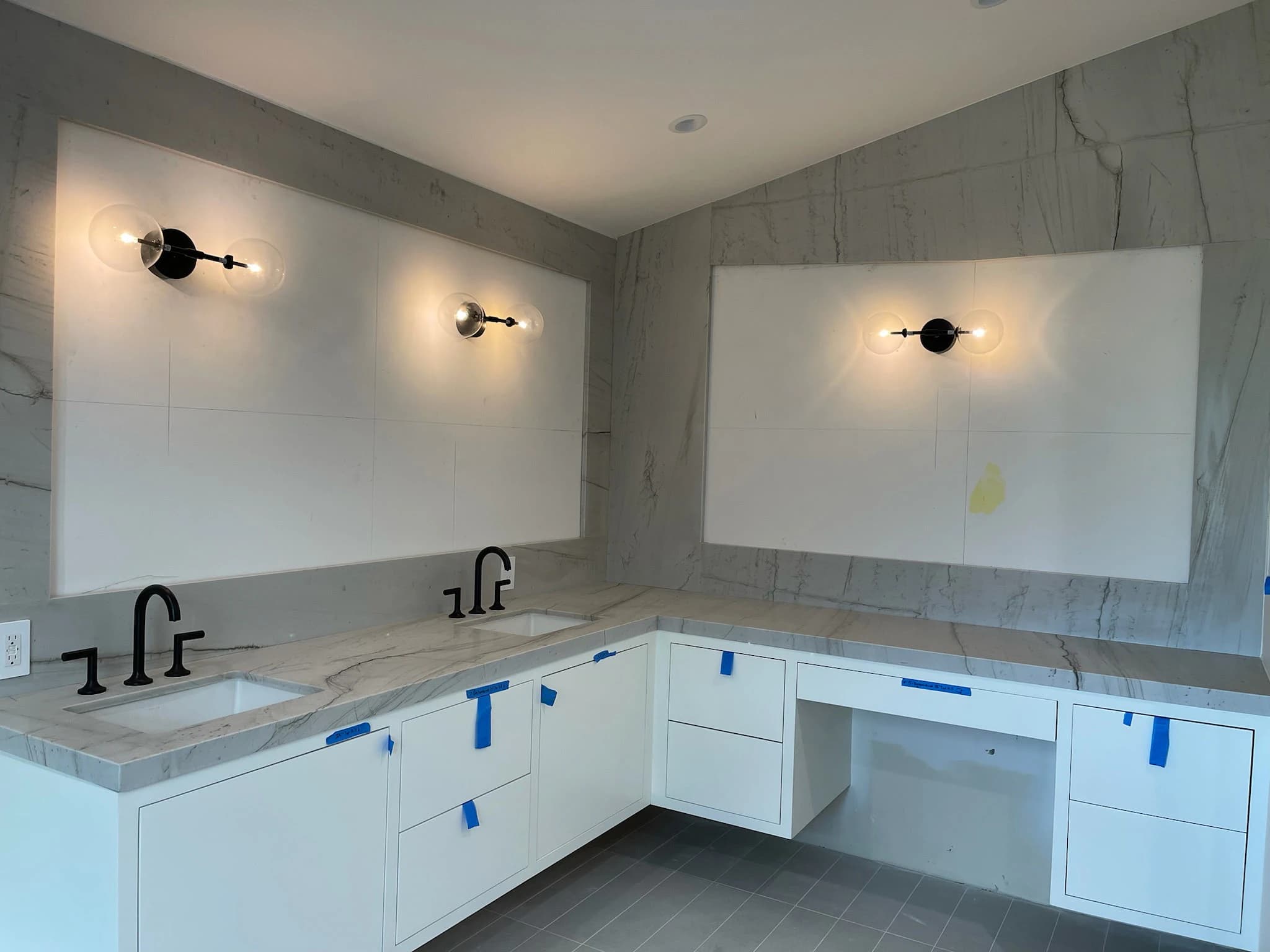 Bathroom vanity installation with stone counters and large-format tiled wall details