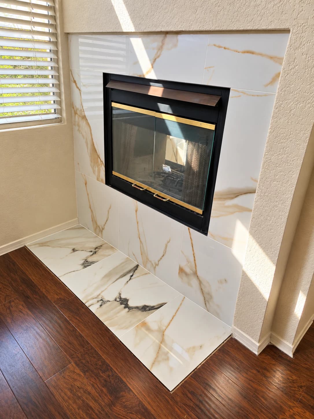 Remodeled fireplace surround and hearth finished with large-format marble-look tile