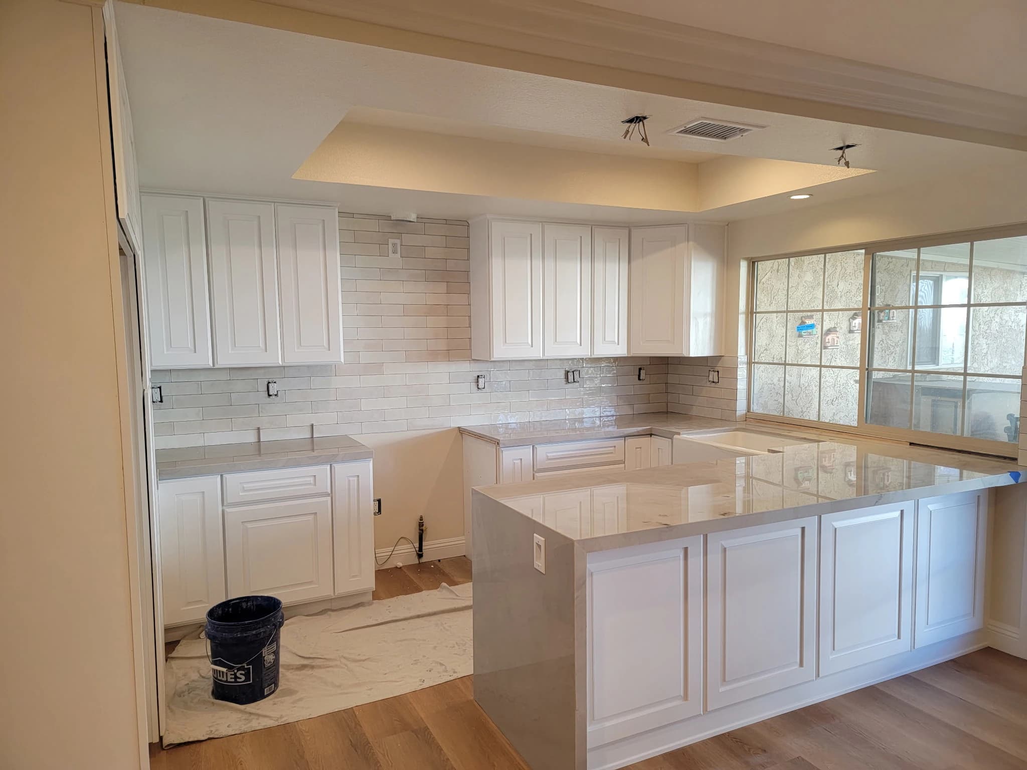 Kitchen installation with stone counters, a tiled backsplash, and a large island