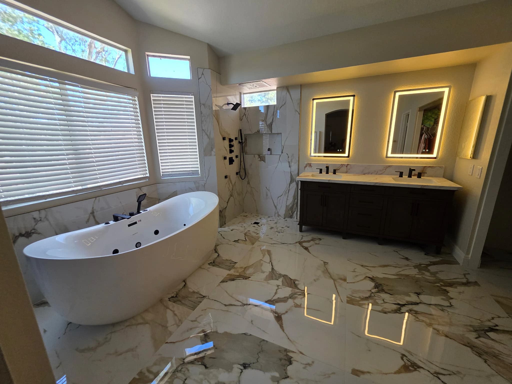 Completed bathroom with marble-look tile, a freestanding tub, walk-in shower, and double vanity