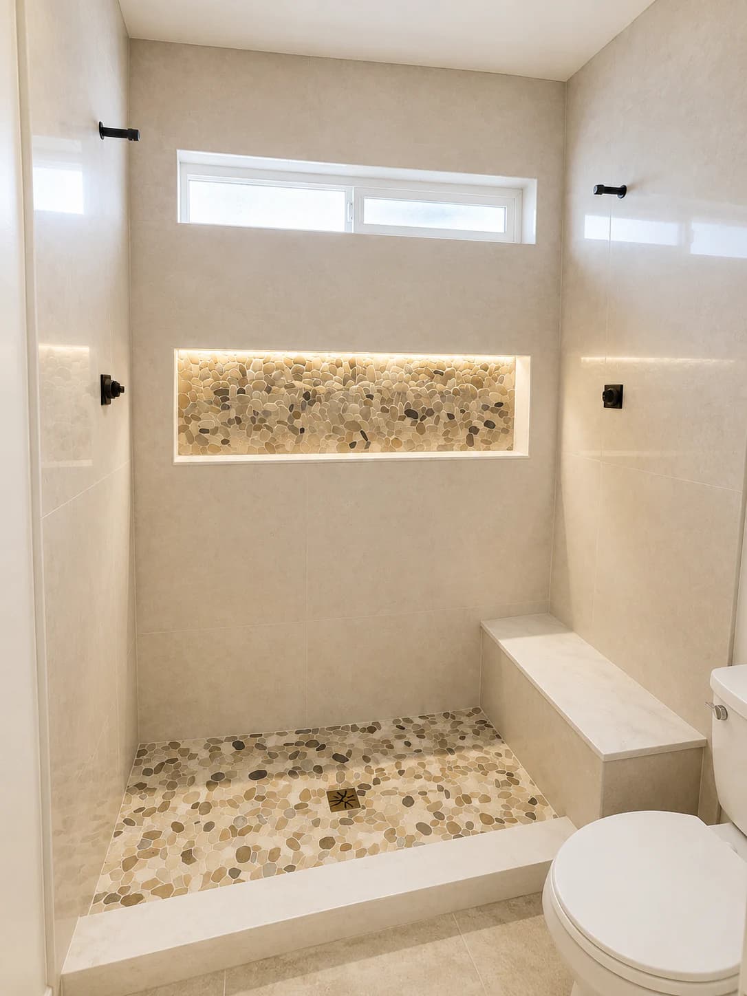 Light-toned shower with an illuminated pebble niche and built-in bench